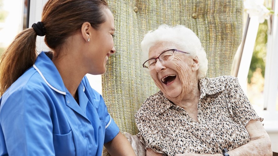 Pflegerin lacht mit älterer Patientin Pflegerin lacht mit älterer Patientin